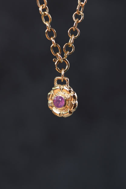 Gold necklace with a purple gemstone pendant on a dark background