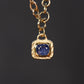 Gold necklace with a blue gemstone pendant on a dark background