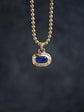 Gold necklace with a blue gemstone pendant on a dark background