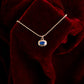 Gold necklace with a blue pendant on a red velvet surface