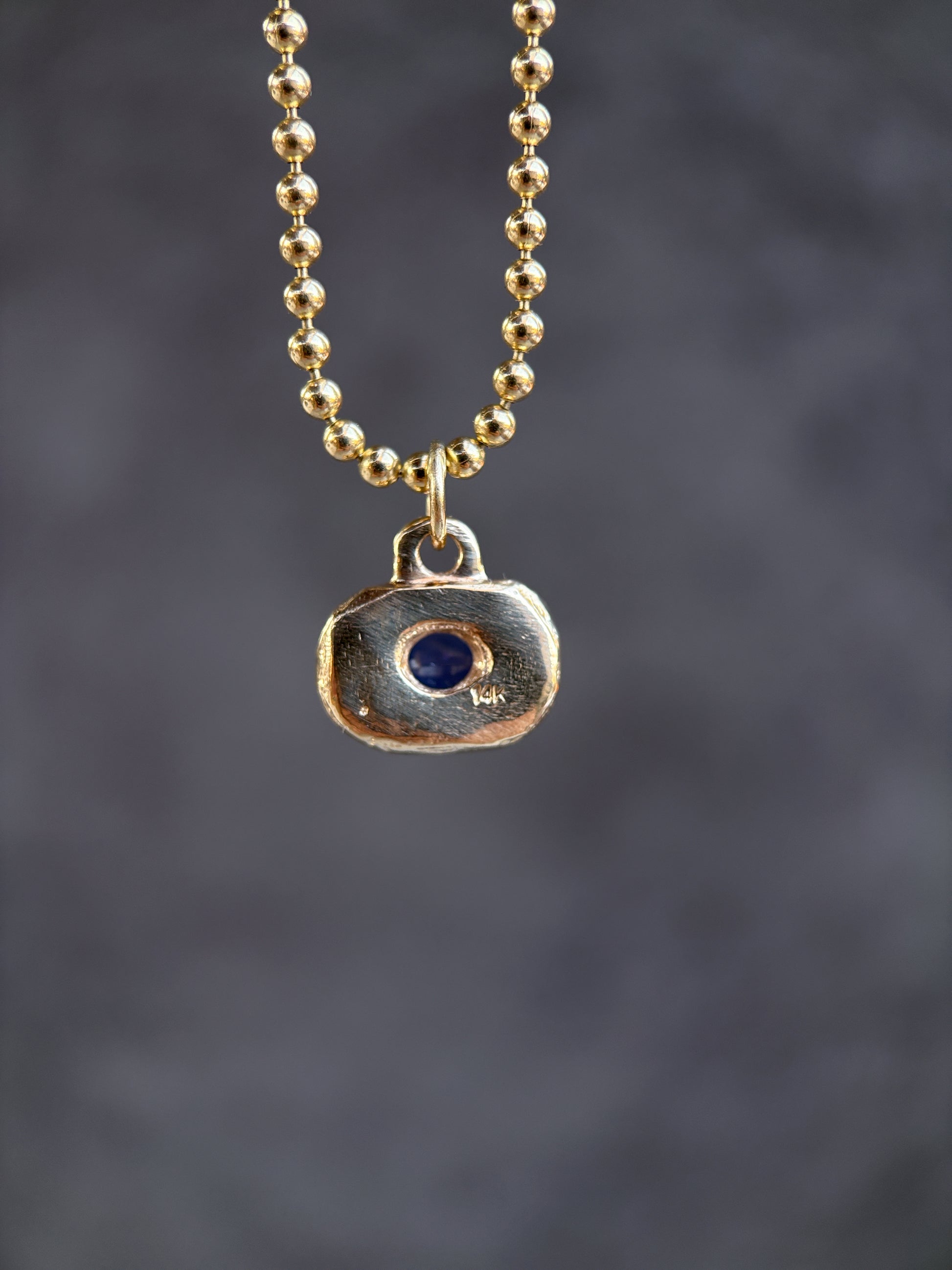 Necklace with a pendant featuring a blue stone on a dark background