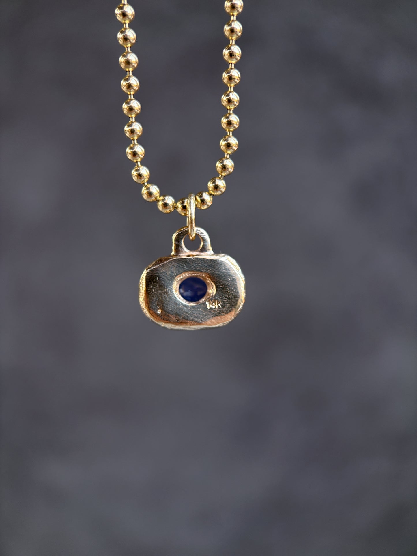 Necklace with a pendant featuring a blue stone on a dark background