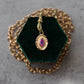 Gold pendant with a purple gemstone on a green velvet stand with a gold chain.