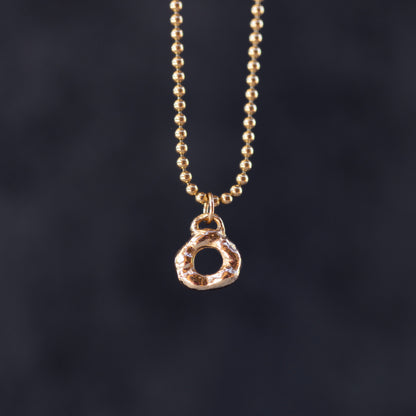 Gold necklace with a circular pendant on a dark background