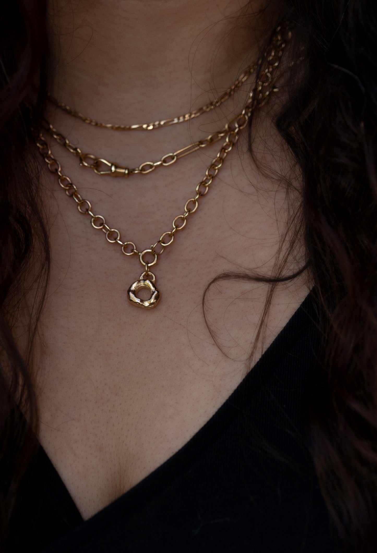 Close-up of a person wearing gold necklaces with a dark background