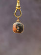 Gold keychain with a small pendant on a blurred gray background