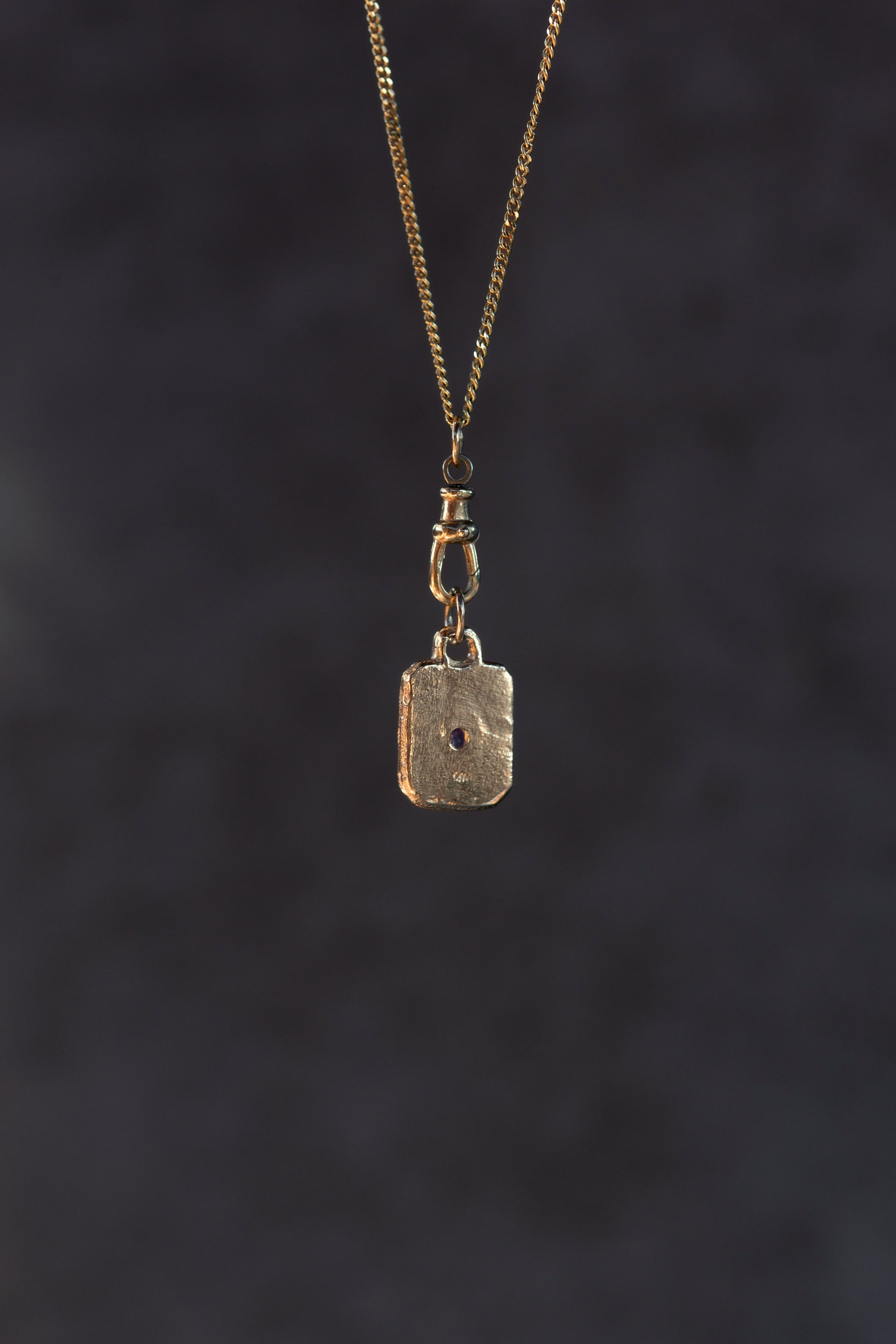 Gold pendant necklace on a dark textured background