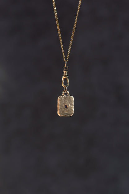 Gold pendant necklace on a dark textured background