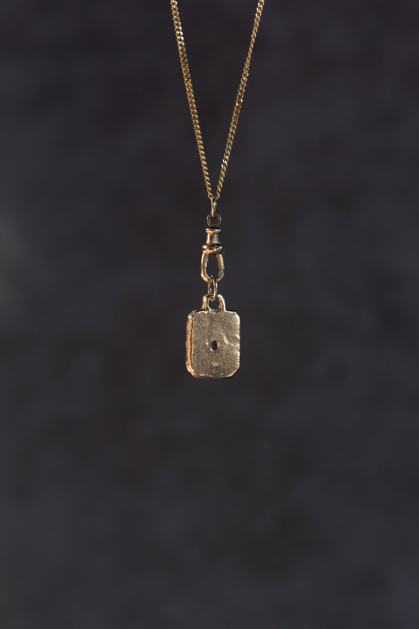 Gold pendant necklace on a dark textured background
