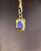 Gold pendant with a blue gemstone on a blurred background