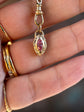 Gold pendant with red gemstones held in a hand