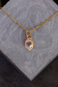 Gold necklace with a pendant on a gray stone surface