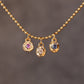 Gold necklace with three pendant charms on a dark background