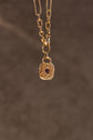Gold necklace with a square pendant on a brown background