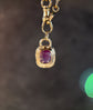 Gold pendant with a red gemstone on a dark background