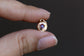Gold pendant with a red gemstone held between fingers against a dark background