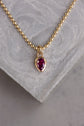 Gold necklace with a red gemstone pendant on a gray stone surface